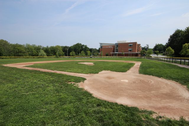 Baseball field with two story brick building in background