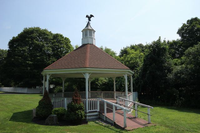 Gazebo in grassy lawn with forest in background