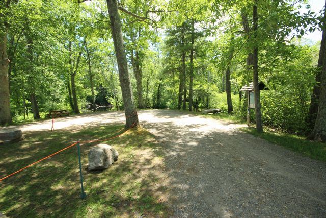 Gravel driveway leading to landing informational board, surrounded by trees